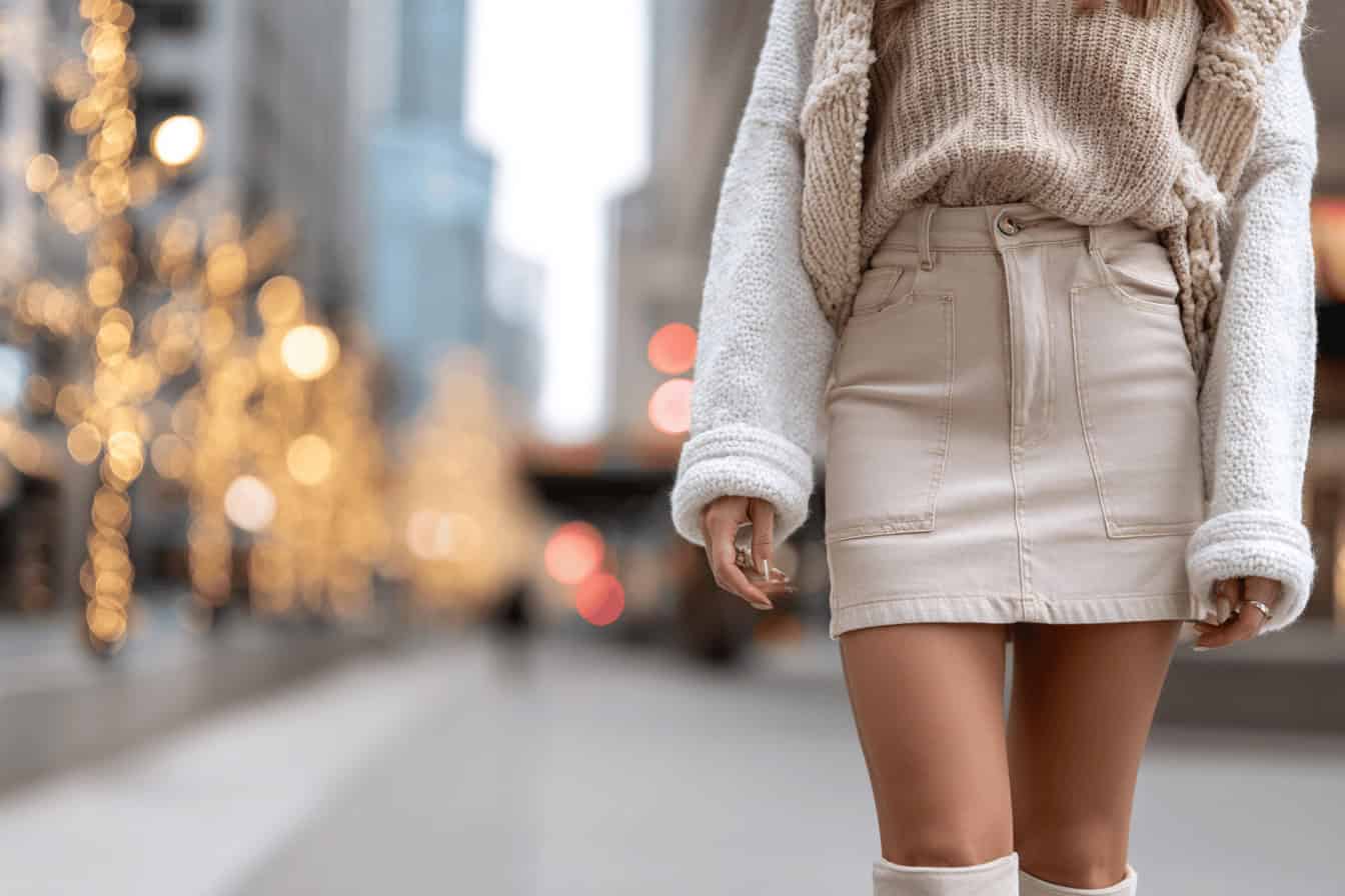 Woman wearing a denim mini skirt with a knit sweater in winter.
