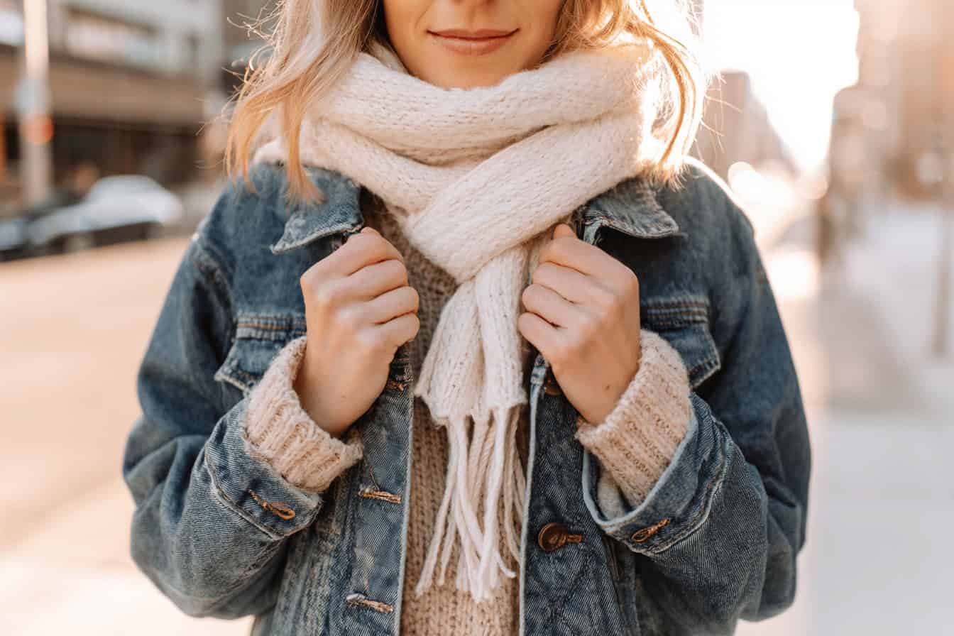 Frau trägt Jeansjacke, Strickpulli und Schal