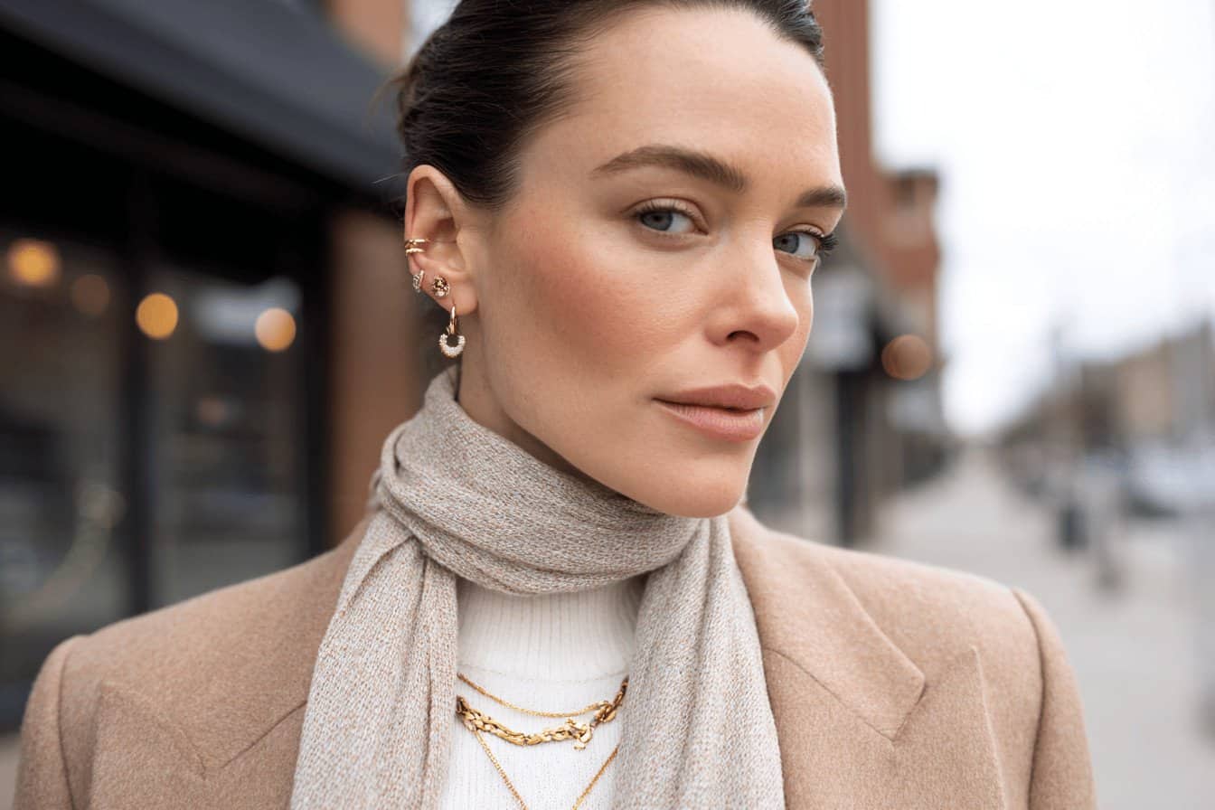 Woman in a beige coat, scarf, and gold accessories